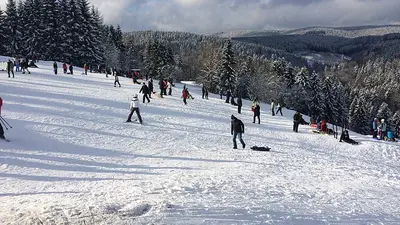 Skifahrer und Rodler auf der Piste im skigebiet Hohegeiß