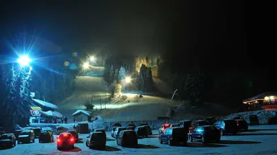 Blick vom Parkplatz auf die beleuchtete Piste