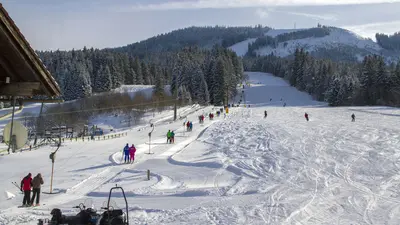 Skifahrer am Schlepplift neben der Piste