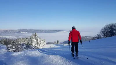 Skifahrer auf der Piste mit Blick ins Tal