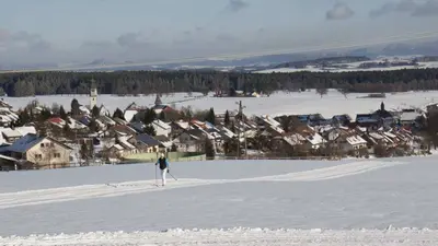 Langläufer auf einer Loipe mit Grafenhausen im Hintergrund