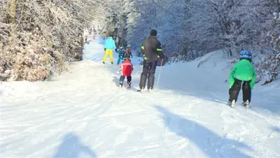 Familie bei der Abfahrt auf der blauen Piste in der Wintersport Arena