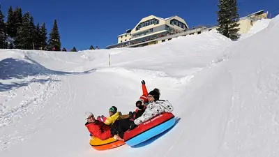 Wintersportler rutschen in riesigen Reifen die Piste im Rutschpark Trübsee herunter