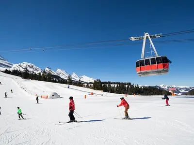 Skifahrer auf einer Piste am Chäserrugg, im Hintergrund die Gondel Ilitos-Unterwasser © Toggenburg Bergbahnen AG