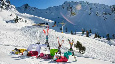 Skifahrer kreuzen ihre Ski vor dem Bergpanorama am Hauser Kaibling