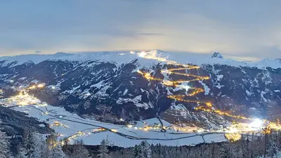 Panoramablick auf Bramberg am Abend mit den beleuchteten Piste