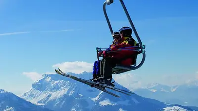 Zwei Skifahrer sitzen in der Sessebahn Hochkössen mit Blick auf die Berge