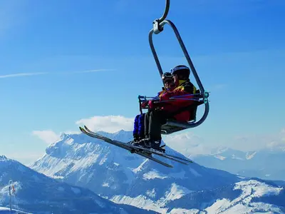 Zwei Skifahrer sitzen in der Sessebahn Hochkössen mit Blick auf die Berge © Marketing Bergbahnen Hochkössen