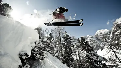 Skifahrer beim Sprung zwischen Bäumen auf einer Freeride-Piste im Skizentrum Schlick 2000