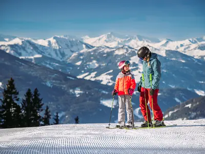 Kind und Frau im Hintergrund eine tolle Aussicht © Snow Space Salzburg/C. Huber