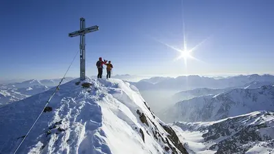 Blick auf zwei Menschen unter dem Gipfelkreuz in Vent