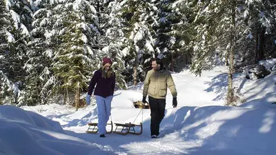 Paar mit Rodel spaziert durch den Schnee in Reutte