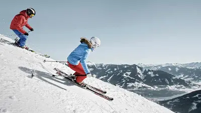 Zwei Skifahrer bei der Abfahrt auf der Piste in Schmitten