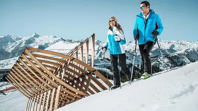 Zwei Schneeschuhwanderer laufen an der Skulptur Schneefalle in Schmitten vorbei