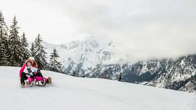 Mutter mit Tocher beim rodeln