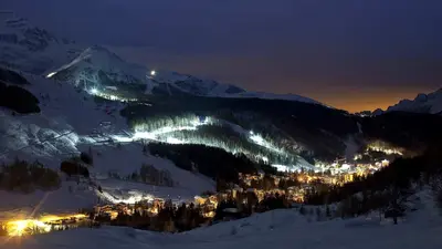 Madesimo bei Nacht mit dem beleuchteten Skigebiet im Hintergrund