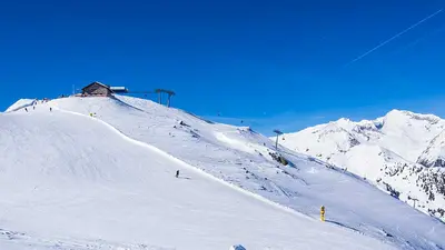 Skifahrer auf Piste am Speikboden mit Hütte im Hintergrund