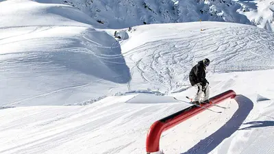 Skifahrer gleitet über Tube im Snowpark Speikboden