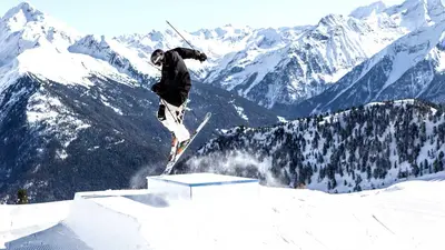 Skifahrer springt über Kicker im Snowpark Speikboden