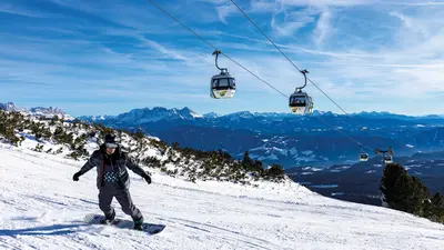Snowboarden mit Blick auf die Gondelbahn am Rittner Horn
