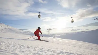 Skifahrerin auf der Piste mit Gondel im Hintergrund