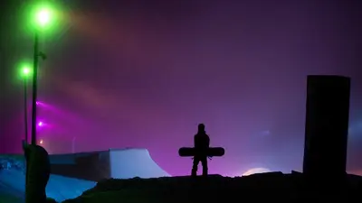 Snowboarder im Snowpark mit bunten Lichtern