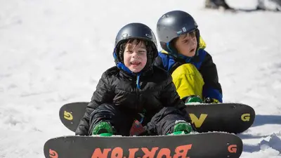Kinder lernen Snowboarden