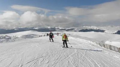 Skifahrer auf der Piste mit Bergpanorama