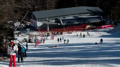 Skifahrer am Schlepplift mit Talstation im Hintergrund
