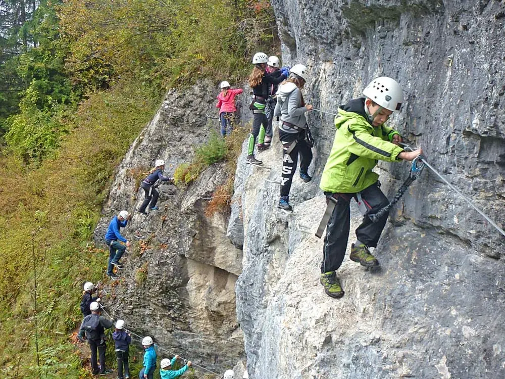 Kinder beim Klettern an einem Klettersteig in Muotathal
