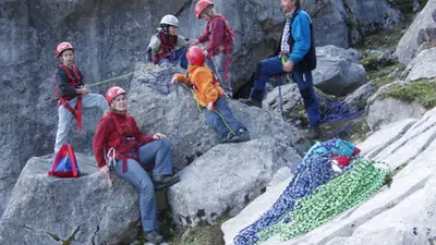 Die Kinder lernen an einfachen Felsen den Umgang mit der Kletterausrüstung