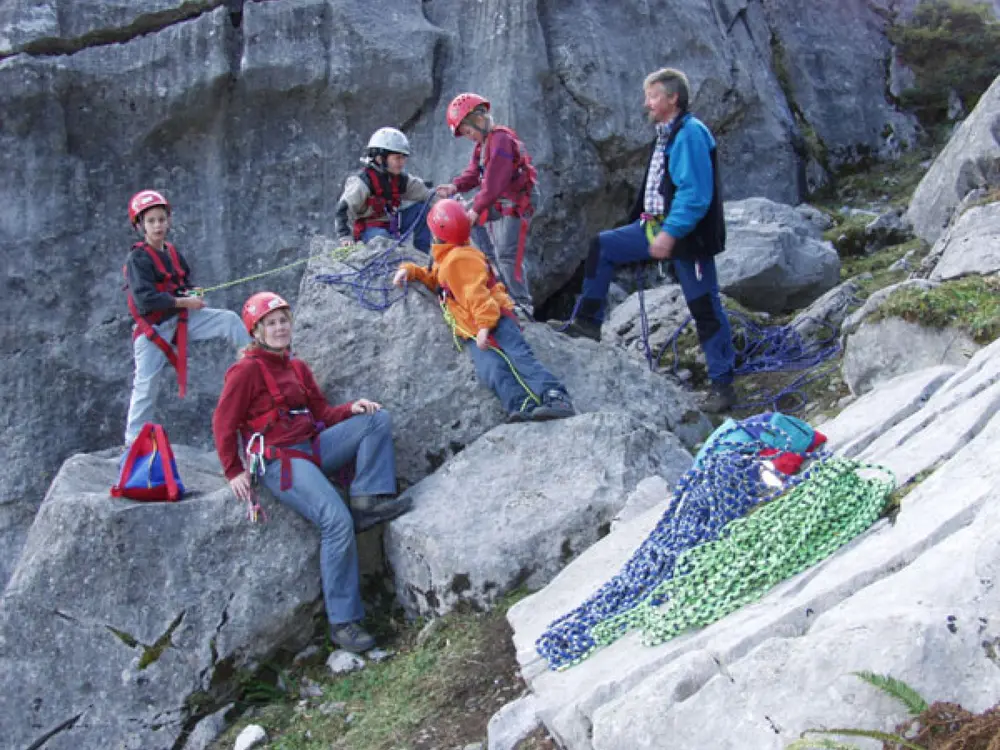 Die Kinder lernen an einfachen Felsen den Umgang mit der Kletterausrüstung