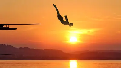 Badegast beim Sprung im Seebad Schenkon bei Sonnenuntergang