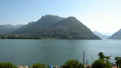 Blick von der Uferpromenade auf den Luganer See mit Alpen im Hintergrund