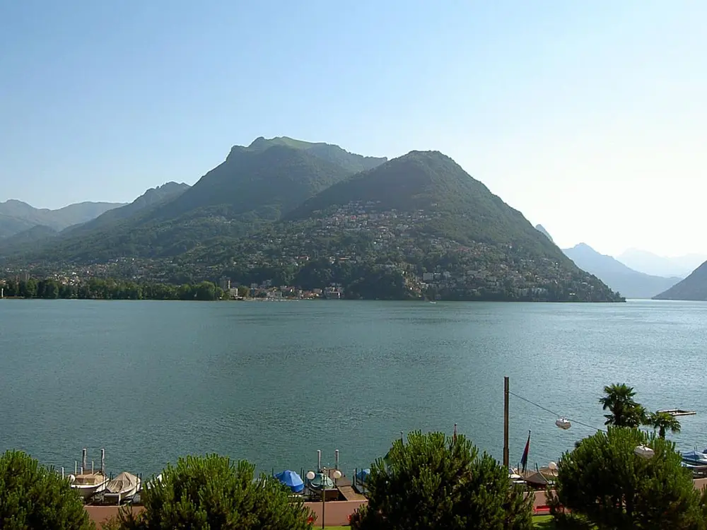 Blick von der Uferpromenade auf den Luganer See mit Alpen im Hintergrund