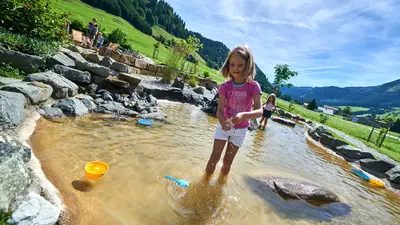 Mädchen auf einem Wasserspielplatz im Tannheimer Tal