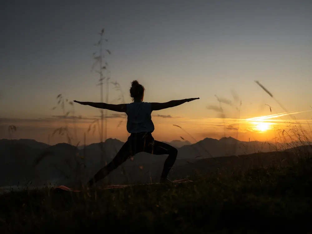 Yoga im Sonnenaufgang auf einer Bergwiese
