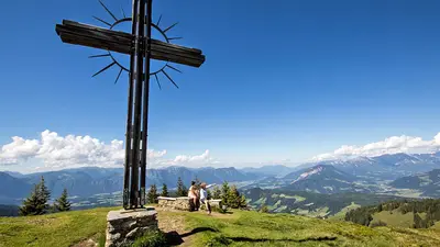 Wanderer unter dem Gipfelkreuz auf dem Rosskopf in der Wildschönau