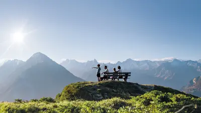 Familie genießt auf einer Bank das Zillertaler Panorama