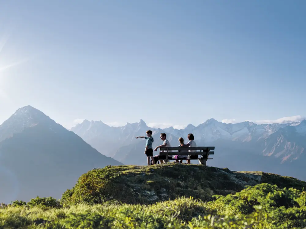 Familie genießt auf einer Bank das Zillertaler Panorama