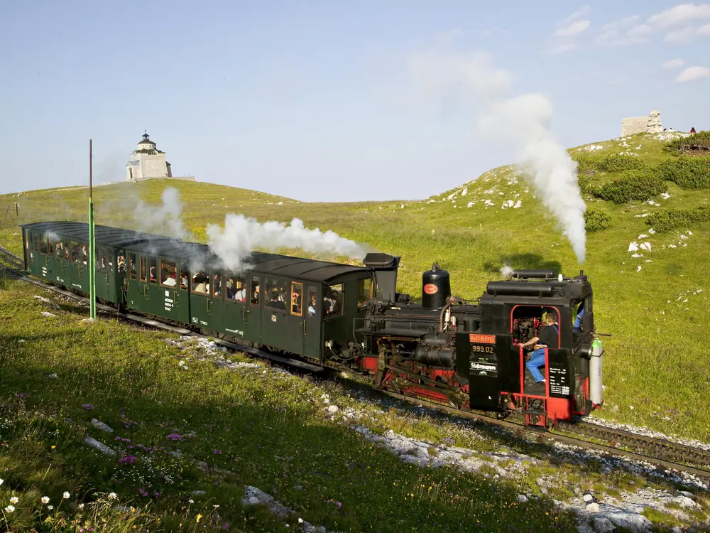 Nostalgie-Dampfzug entlang einer blühenden Bergwiese im Frühling