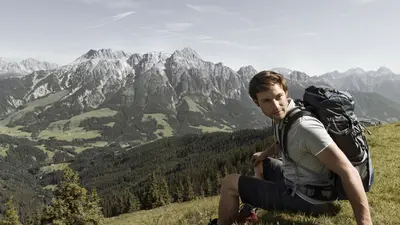 Wanderer bei einer Rast mit Panoramablick auf die Leoganger Steinberge