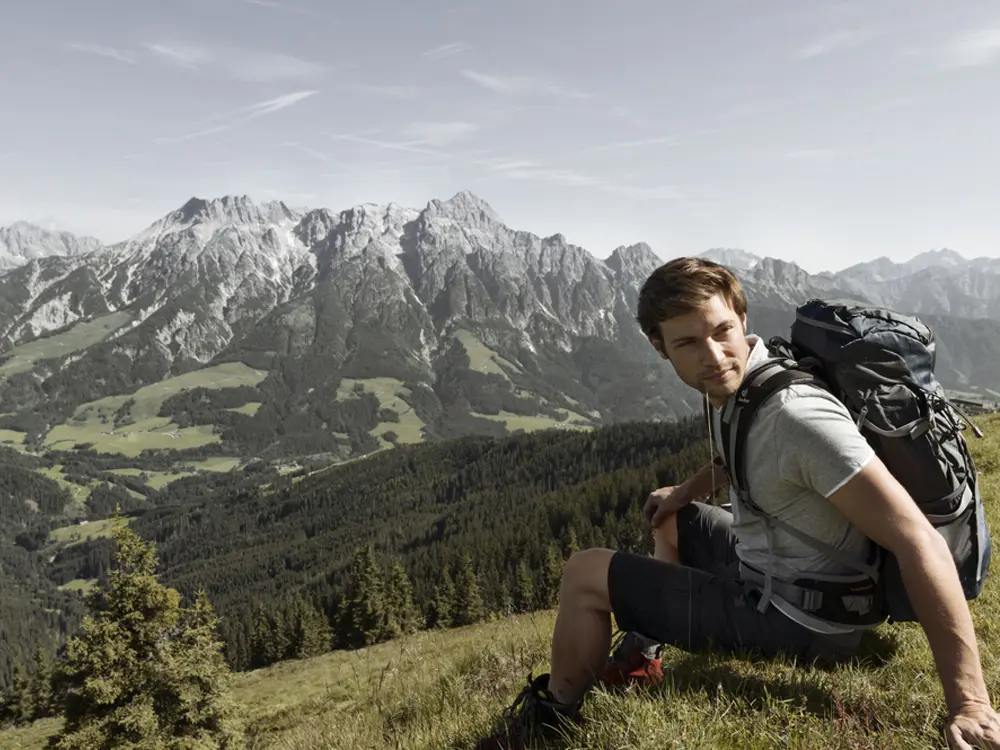 Wanderer bei einer Rast mit Panoramablick auf die Leoganger Steinberge
