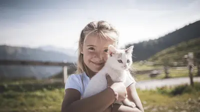 Glückliches Kind mit einer Katze auf der Alm