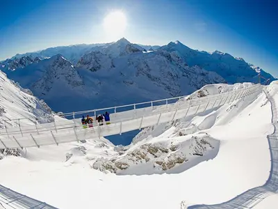 Vier Wintersportler genießen die Aussicht auf der Hängebrücke Cliffwalk in Titlis © Engelberg-Titlis Tourismus AG