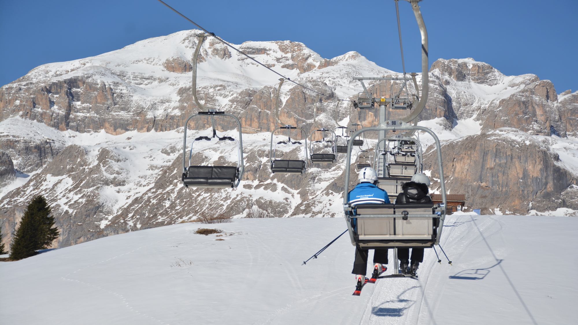 Gemütliche Sesselliftfahrt: Bei der Auffahrt zum Monte Cherz (2088m) begeistert die Aussicht nach Westen zu den Felswänden des Sella Stocks.