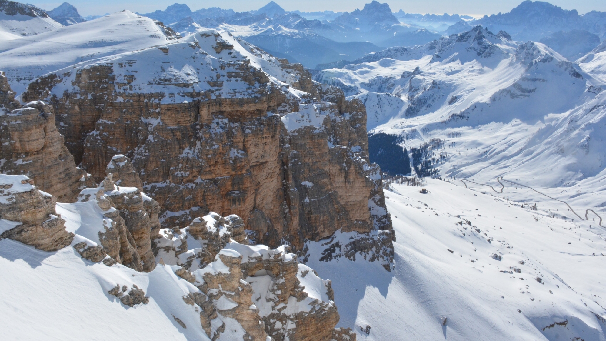 Blick von der Bergstation am Sass Pordoi (2950m) auf die Große Dolomitenstraße östlich des Pordoipasses. Im Hintergrund von rechts nach links: Civetta (3220m), Monte Pelmo (3172m), Antelao (3264m) und Sorapiss (3205m)