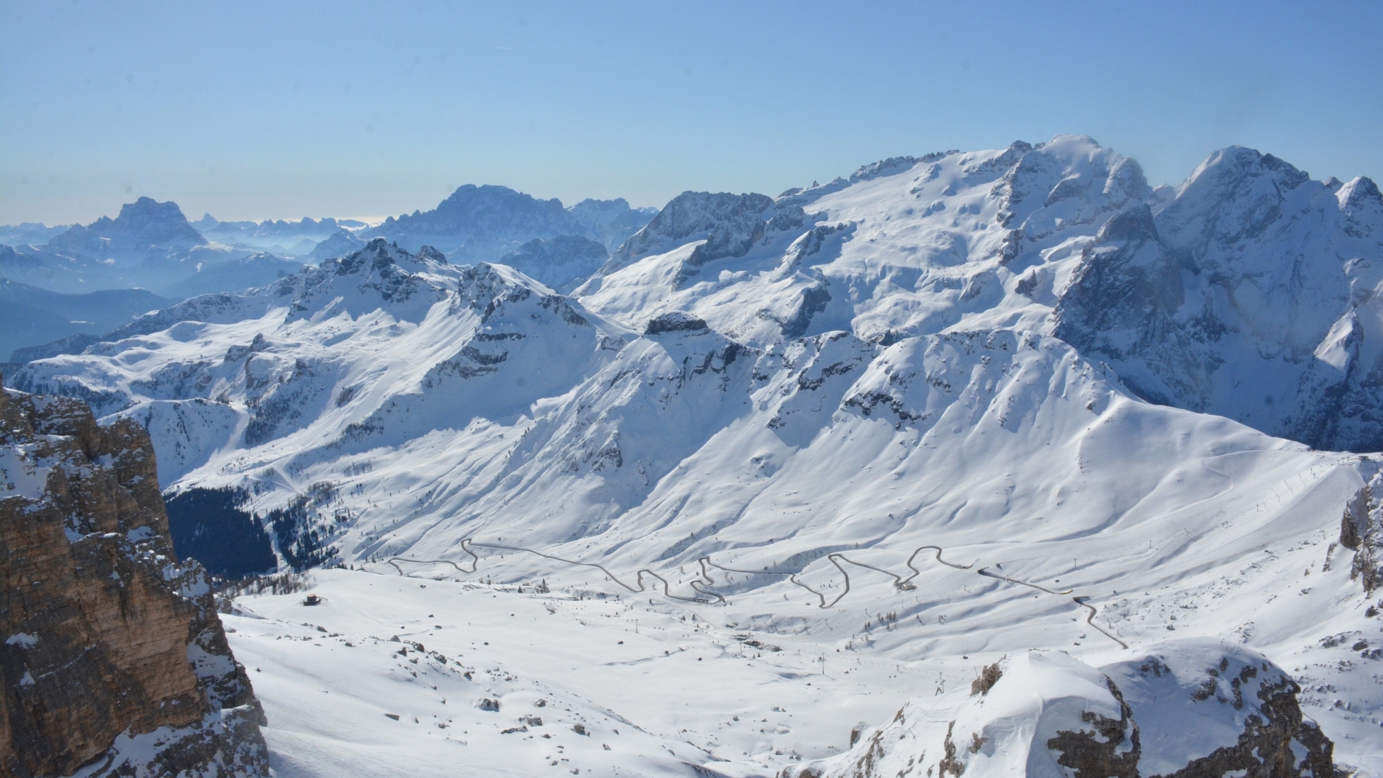 Blick von der Bergstation am Sass Pordoi (2950m) auf die Große Dolomitenstraße östlich des Pordoipasses. Im Hintergrund von rechts nach links: Gran Vernel (3210), Marmolada (3343), Civetta (3220m), Berge der Bosconero-Gruppe, Monte Pelmo (3172m)