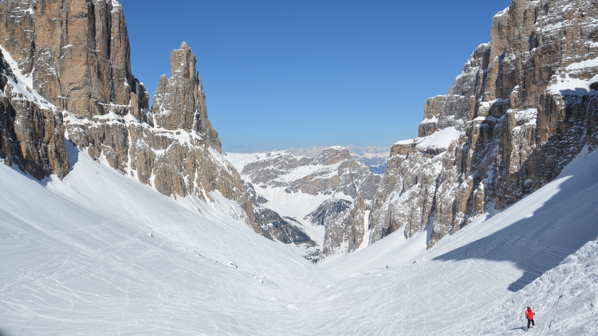 Skiabfahrt durch das Mittagstal auf ca. 2500 m Höhe mit Blick nach Norden, flankiert von den Felsspitzen Sas de Mesdi (2980m) und Bech des Mesdi (2962m), noch sind fast 900 Höhenmeter Abfahrt bis Kolfuschg (ca. 1600m) zu bewältigen
