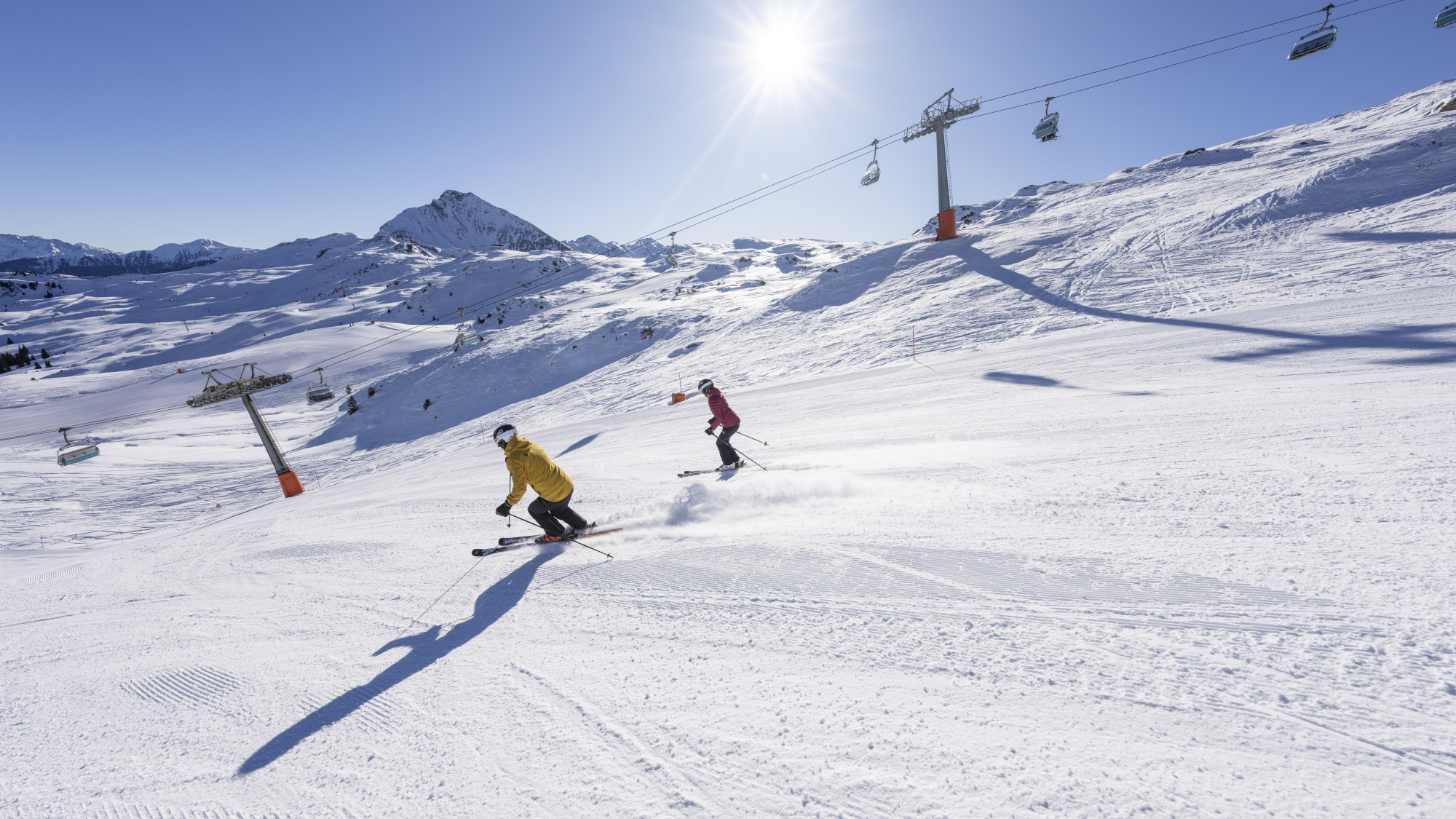 Skifahrer gleiten bei klarem Wetter eine schneebedeckte Abfahrt in Ratschings-Jaufen hinunter.
